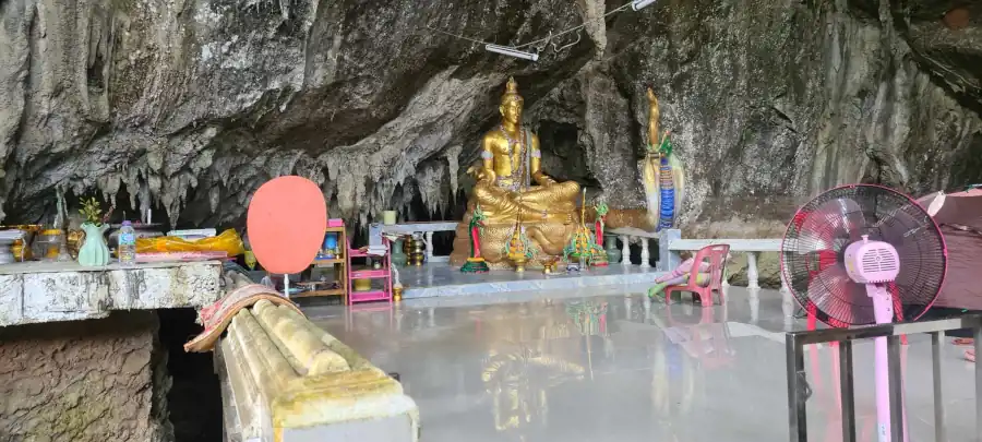 Buddha statue shrine inside a limestone cave temple with stalactites and rock formations