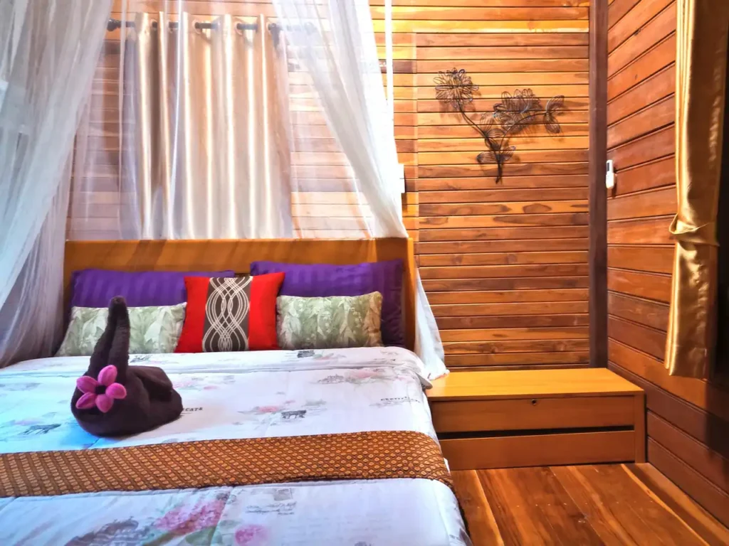 Inviting Krabi holiday home bedroom with large canopy bed and traditional wood paneled walls and floors