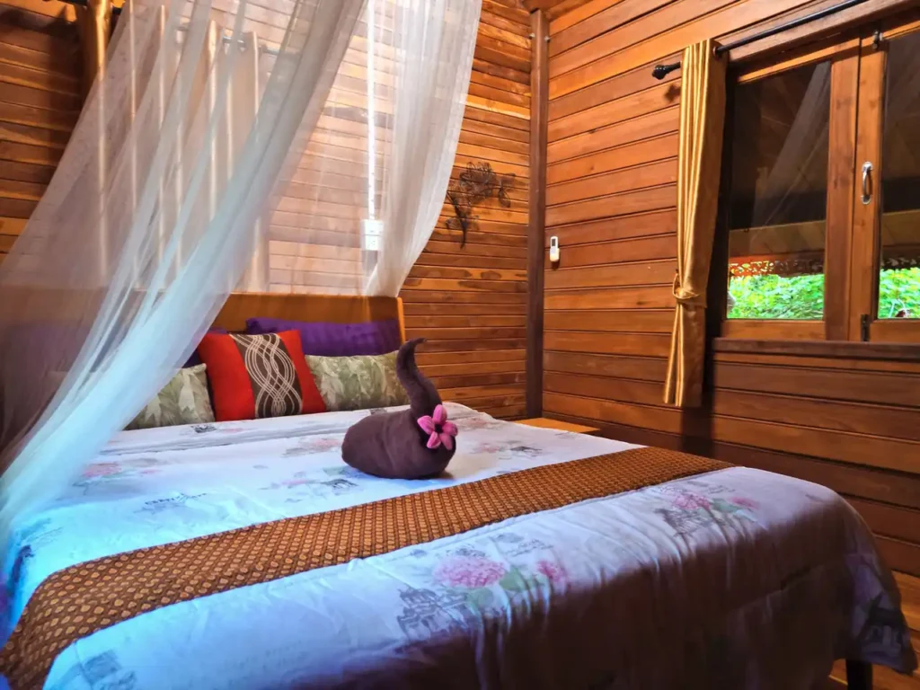 Warm Krabi teak house bedroom with rustic wooden walls and garden view