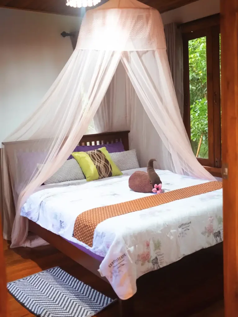 Rustic Krabi teak house bedroom with mosquito net canopy and garden outlook
