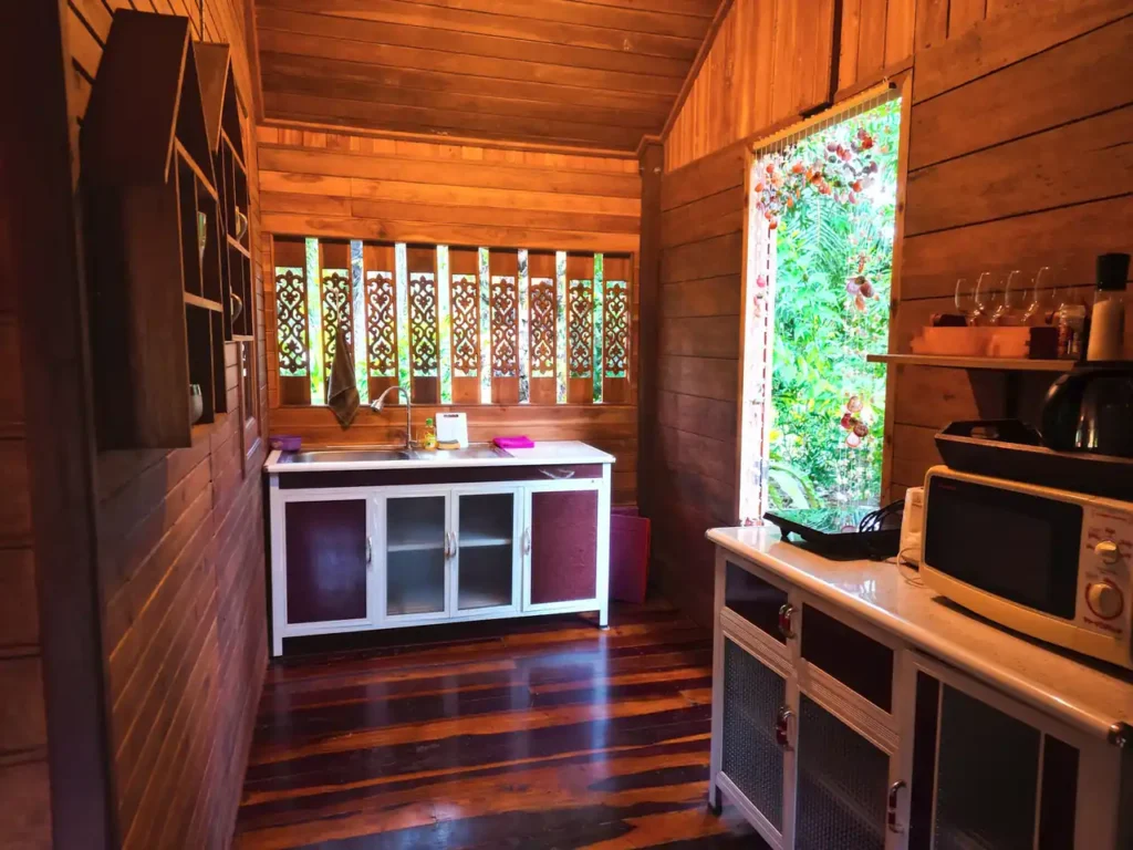 Traditional Krabi teak house kitchen with carved panels and garden view