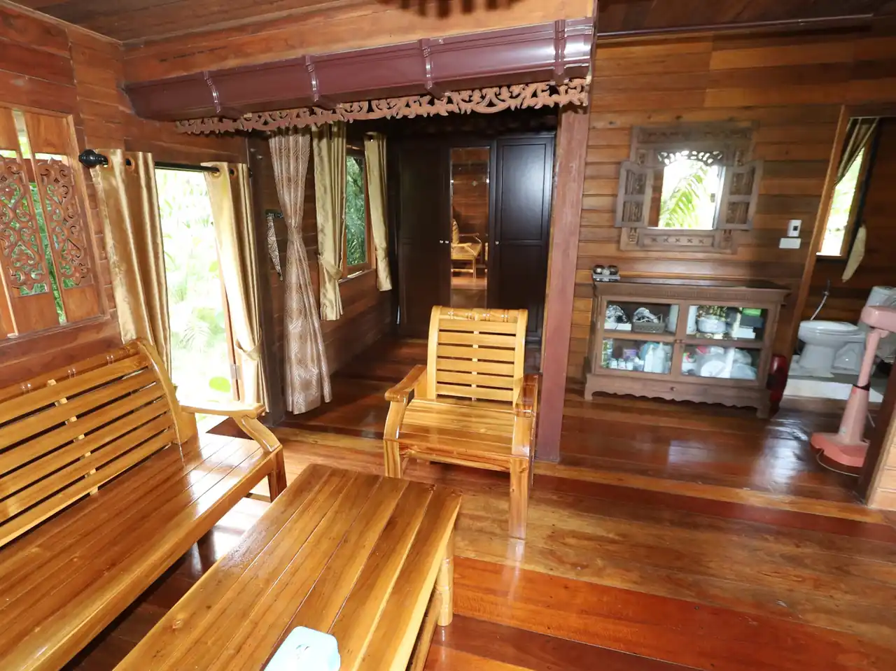 Tropical Krabi teak house living space with wooden furniture and garden outlook
