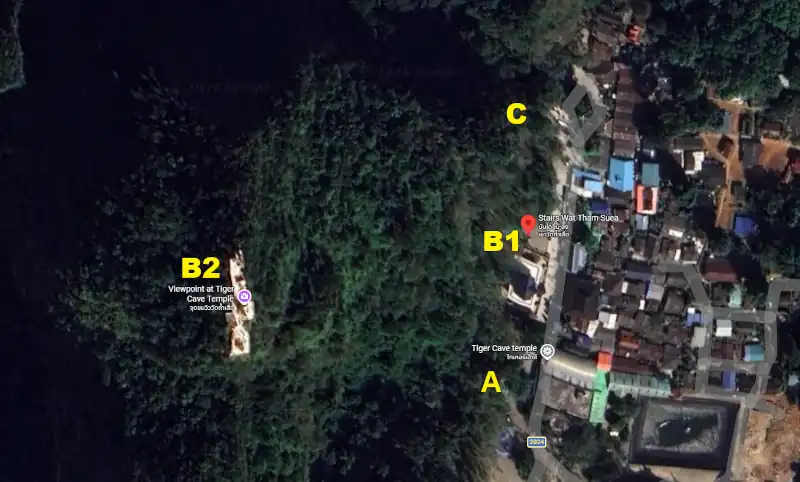Aerial view of forested hillside with temple structures, stairways, and pathways surrounded by dense greenery.